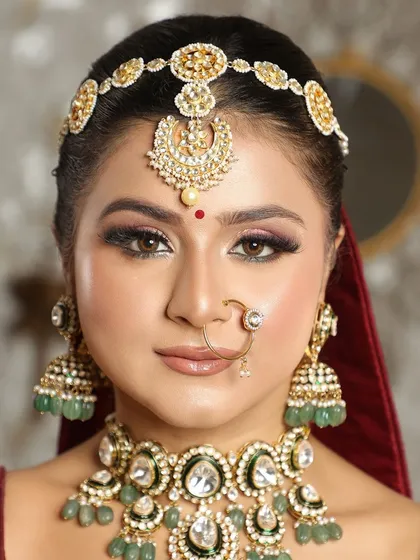 A detailed shot of a traditional bridal look, focusing on the rich colors of the jewelry and the perfectly sculpted makeup that enhances her features.