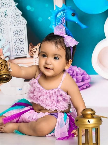 This little mermaid is discovering treasures from the deep sea. The colorful tail and underwater-themed props create a vibrant and imaginative scene.