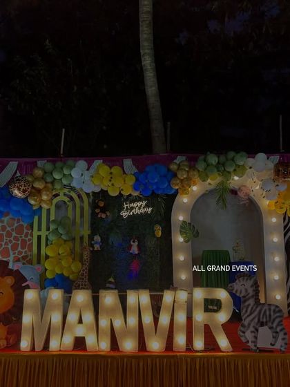 A fun jungle safari theme for Manvir's birthday. The outdoor stage includes animal print backdrops, cute animal cutouts like a lion and zebra, and large marquee letters.
