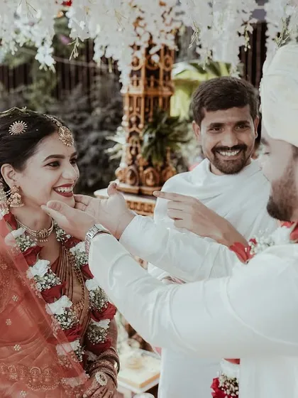 The groom playfully applies a touch to the bride's cheek, a sweet, unscripted moment during the wedding ceremony that brings out genuine smiles.