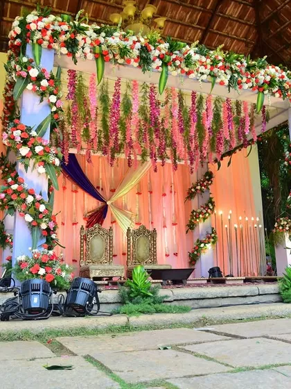 An elegant outdoor wedding mandap set against the natural beauty of a resort. We used a mix of vibrant flowers, flowing drapes, and soft lighting to create a romantic and serene setting for the ceremony.