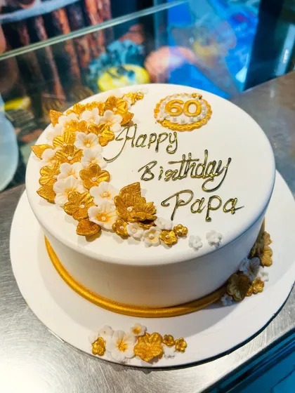 A classy 60th birthday cake for "Papa," featuring elegant white and gold sugar flowers.