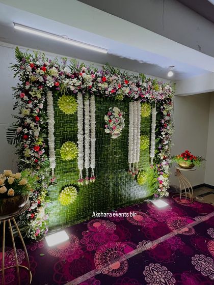 This elegant naming ceremony backdrop is made from woven banana leaves and adorned with garlands of fresh white jasmine. The floral frame adds a touch of grandeur to the setting.