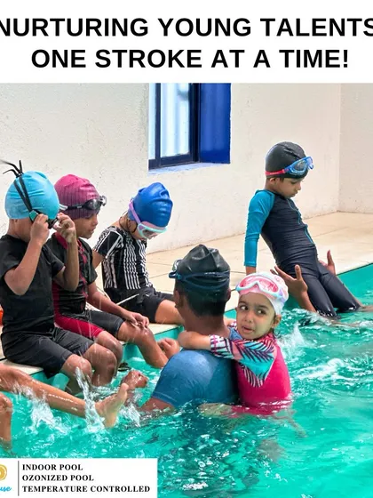 We nurture young talents one stroke at a time. This image shows kids learning the basics at the edge of the pool, a key step in building their swimming foundation.