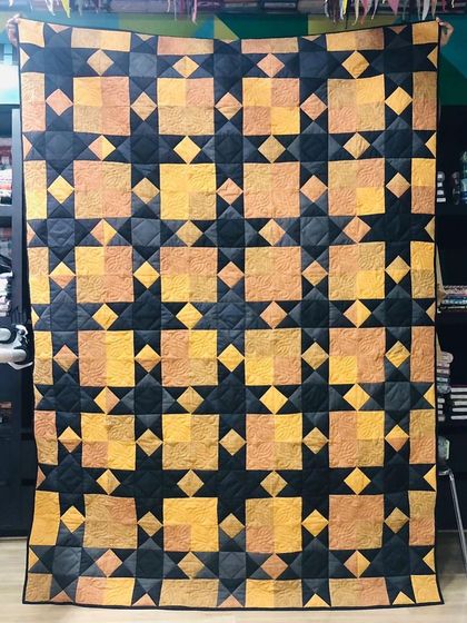 A Sawtooth Star memory quilt made with suits and blenders, featuring a striking black and gold design.