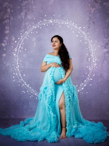A vibrant and joyful portrait. This bright blue ruffled gown stands out beautifully against the lavender backdrop, creating a modern and stylish maternity look.