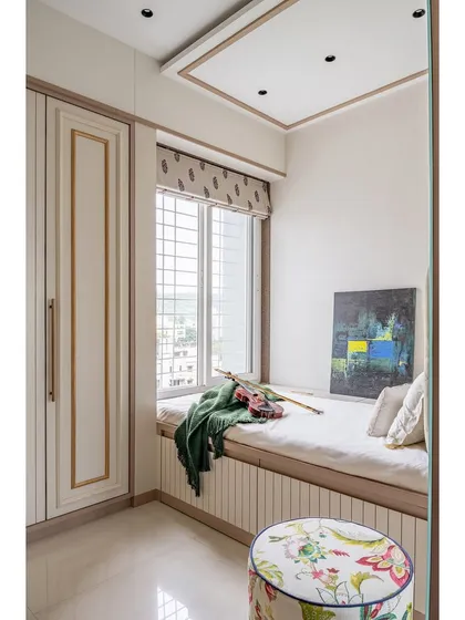 This shot highlights the clever use of a window seat bed and a floral-patterned ottoman, creating a subtle, warm, and highly functional small space.