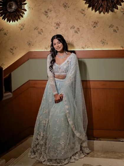 A lovely portrait of the bride standing against a softly lit, patterned wall. Her gentle smile and poised stance create a picture of grace and elegance.