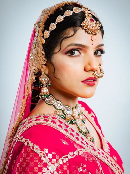 A striking profile shot of the bride, showing off the intricate details of the maang tikka and the large, traditional nose ring.