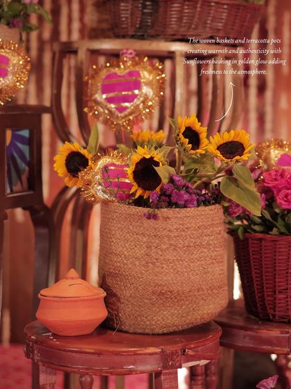 A detail shot showing sunflowers in a jute basket next to a terracotta pot, highlighting the warm and authentic textures of the decor.