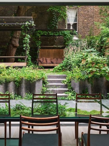 A view from the dining room looking out onto a multi-tiered garden. We design landscapes that serve as a beautiful backdrop to your indoor living spaces, connecting the home with nature.