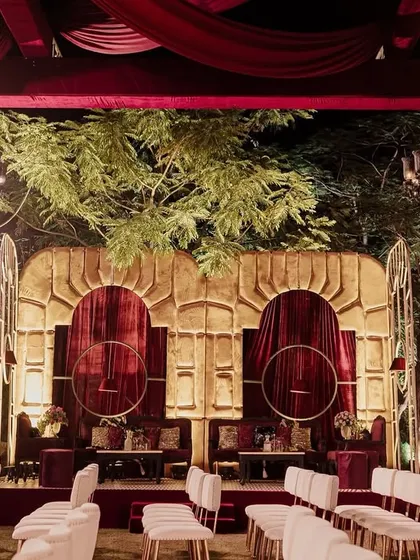The stage for the Sangeet was set against a backdrop of lush, natural greenery. We designed a custom gold-and-velvet structure that felt both grand and integrated with the outdoor setting.