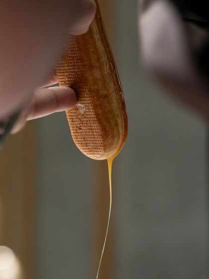 Filling a freshly baked éclair shell. The key is a light choux pastry and a delicious, stable cream filling, both of which you'll master in our classes.