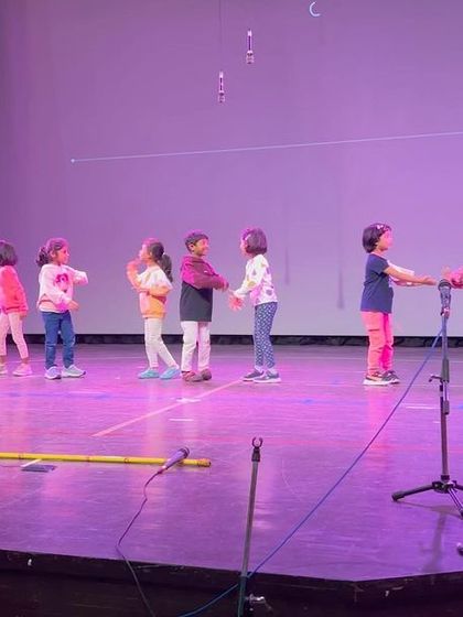 A group of girls practices their choreography on stage, learning about teamwork and coordination.