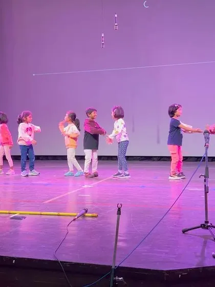 Another view of our students rehearsing on stage, holding hands and practicing their formation for a dance number.