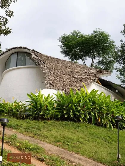The 'Earth's Embrace' eco-retreat by Raving Dots Studio features a sculptural ferrocement shell with a thatched roof that blends organically with the hillside.