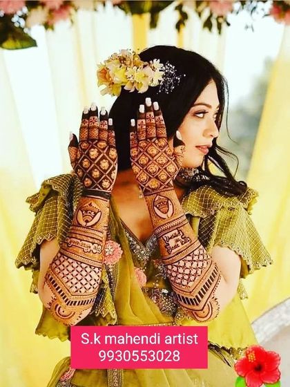 A stunning photo of a bride on her mehendi day. She is beautifully showcasing the intricate jaal work on her hands.