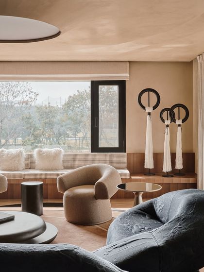 This seating area is defined by its mix of sculptural furniture and art pieces. The large window floods the space with natural light, creating a calm and inviting atmosphere for relaxation.