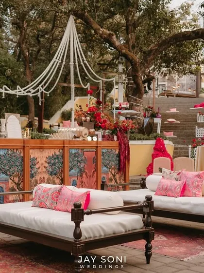 A view of the main lounge area with traditional daybeds and a beautifully painted bar, showing the different zones created for the Mehfil-e-Mehendi.