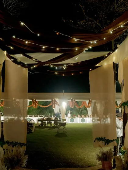 An inviting entrance tunnel created with earthy-toned fabrics and strings of fairy lights, leading guests into the main event area.