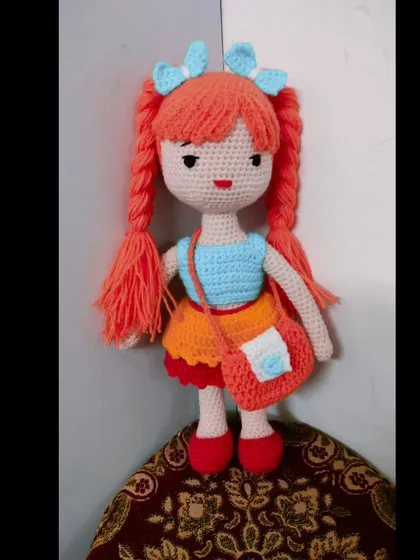 A beautiful doll with bright orange hair in pigtails. Her dress is a mix of orange and blue.