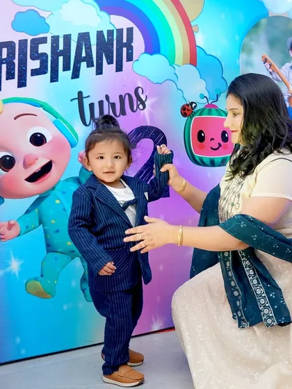 A mother helps her son, dressed in a smart suit, pose in front of a colorful Cocomelon birthday banner. We always make time for those cherished parent and child photos.