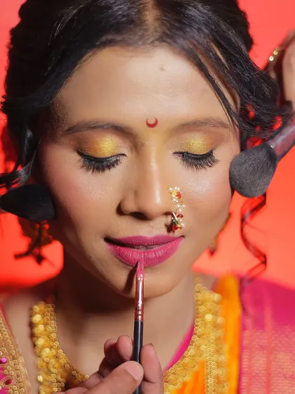 A closer look at the application process. Here, I am defining the lips while another brush sets the cheek makeup. Learning to multitask with precision is a skill we build in my professional makeup courses.