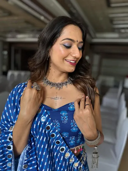 A soft glam look perfect for a Navratri Garba night. The makeup features a subtle blue shimmer on the eyes to match her indigo lehenga, paired with a natural, glowing base.