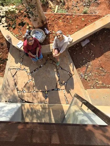 A moment of quiet collaboration, laying tile inserts into the stone flooring by the tree. These small, handmade details are what give a space its unique character and warmth.