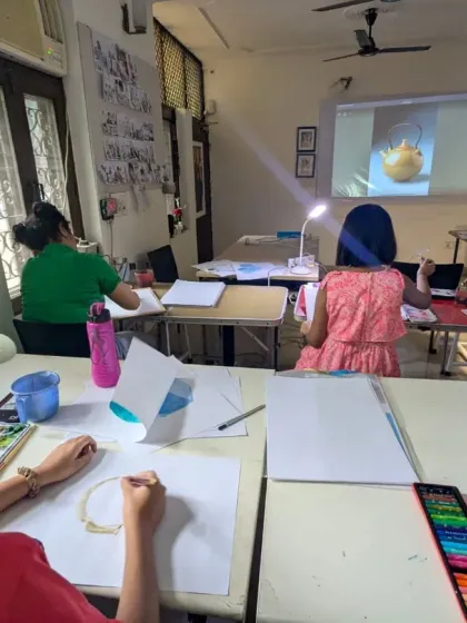 A focused classroom session on still life. Our teen students are learning to observe and draw an apple, with a digital reference projected to help guide them.