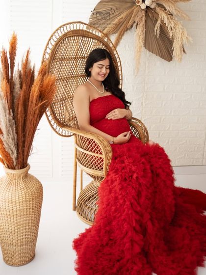 A regal solo portrait in the peacock chair. The vibrant red gown spreads out beautifully, making the mother-to-be look like royalty.