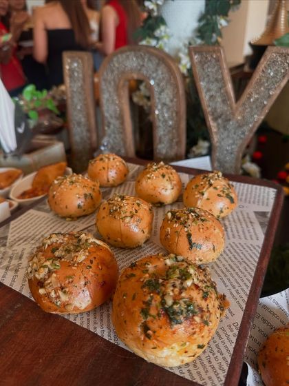 Freshly baked garlic buns, presented on newsprint-style paper for a rustic-chic touch. These were part of a larger themed setup, adding a delicious, aromatic element to the feast.
