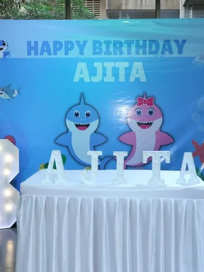 The main cake-cutting stage for the Baby Shark party. The setup includes a large character backdrop, a light-up number '3', and a custom-lettered name display.