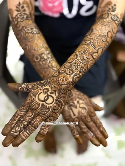 A closer look at the personalized palms, with the initials and ring motif clearly visible within the intricate henna pattern.