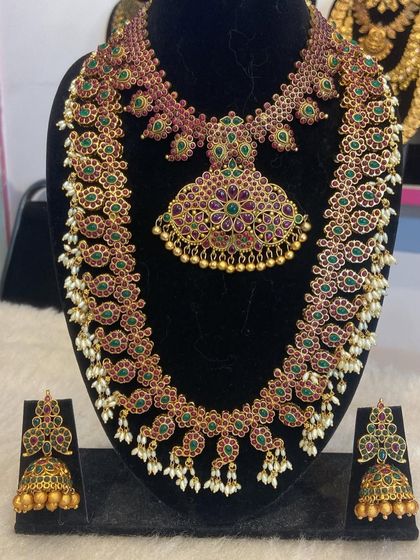 A grand mango-motif haram and necklace set with ruby and green stones. The pearl drops add a touch of elegance to this traditional design.