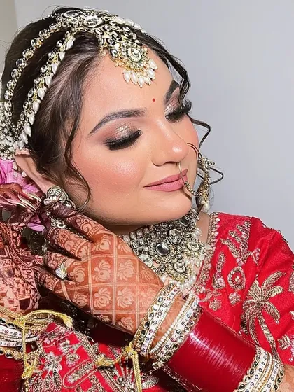 The final touches make all the difference. Here, the bride adjusts her earring, showing off her intricate henna and perfectly manicured nails, which are all part of the complete bridal look.