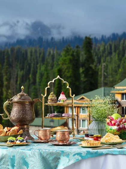 This stunning high tea setup was photographed on location at The Khyber Resort in Gulmarg. The majestic mountain backdrop adds a unique sense of place to the beautifully styled table of pastries, tea, and local delicacies.
