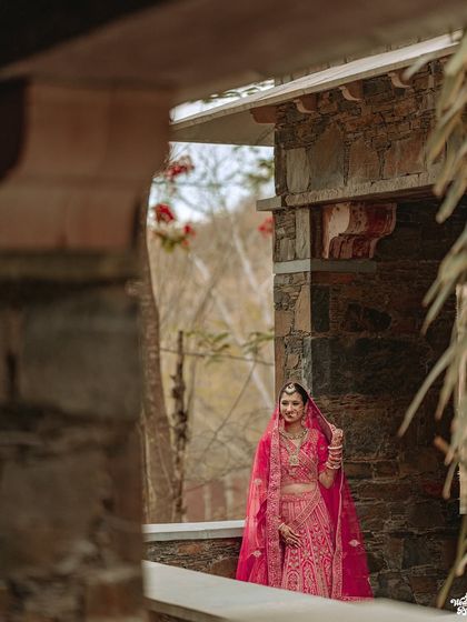 A stunning shot of the bride framed by the stone architecture of her wedding venue.