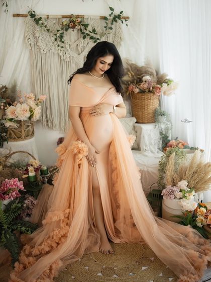 A full-length portrait showcasing the beautiful flow and detail of the peach tulle gown. The mother-to-be looks like she's floating in a dream.