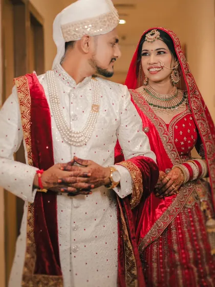A classic portrait of a smiling couple. Their coordinated red and white outfits look stunning, and their happy expressions tell their story.