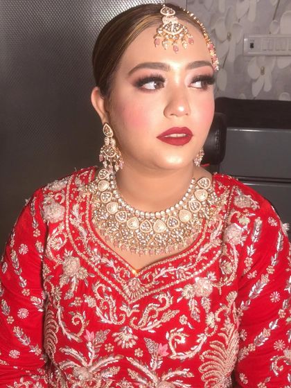 Beauty at its best. A close-up of our bride's stunning makeup, featuring bold red lips and defined eyes that perfectly complement her red embroidered outfit and polki jewelry.