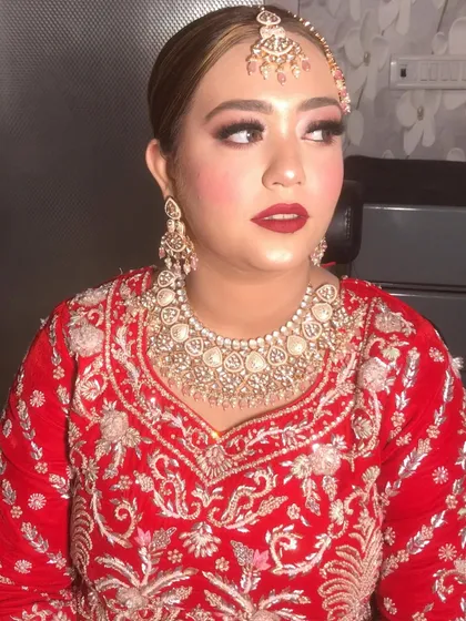 A close-up of our beautiful bride. Her classic red bridal look features a bold red lip, defined eyes with winged liner, and radiant skin, complemented by her stunning jewelry.