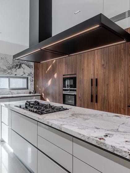 The custom-designed Falmec chimney hood is both a functional appliance and a sculptural element, perfectly complementing the scale and style of the island cooktop.