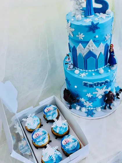The two-tier Frozen cake with a box of matching themed cupcakes.