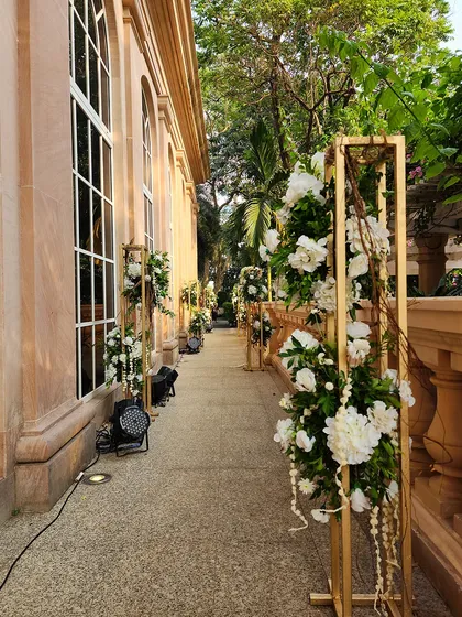 A long walkway lined with elegant floral arrangements on gold stands. This design creates a beautiful and sophisticated path for guests, guiding them towards the main event area.