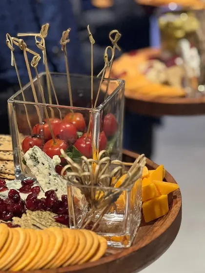 A detail shot of a grazing board, focusing on the variety of textures and colours from blue cheese, cheddar, cherry tomatoes, and assorted crackers.