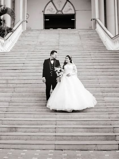 A grand, wide-angle black and white shot of the couple on the church steps. The scale of the architecture makes for a dramatic wedding portrait.