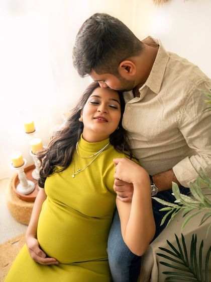 A moment of pure peace and connection. The husband’s gentle kiss on his wife's forehead captures the protective and loving energy of their partnership during this special time.