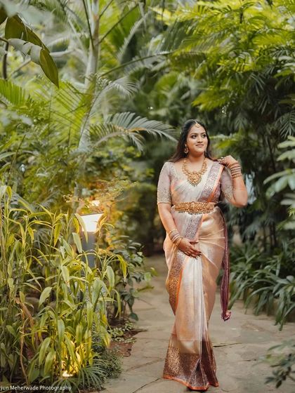 A full-length shot of the bride walking in a garden. The pastel colors of her saree and the delicate embroidery make this a truly romantic bridal look.