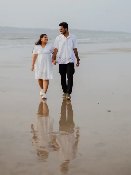 A beautiful reflection shot of the couple walking on the wet sand at sunset. This composition adds an artistic and serene quality to the pre-wedding album.